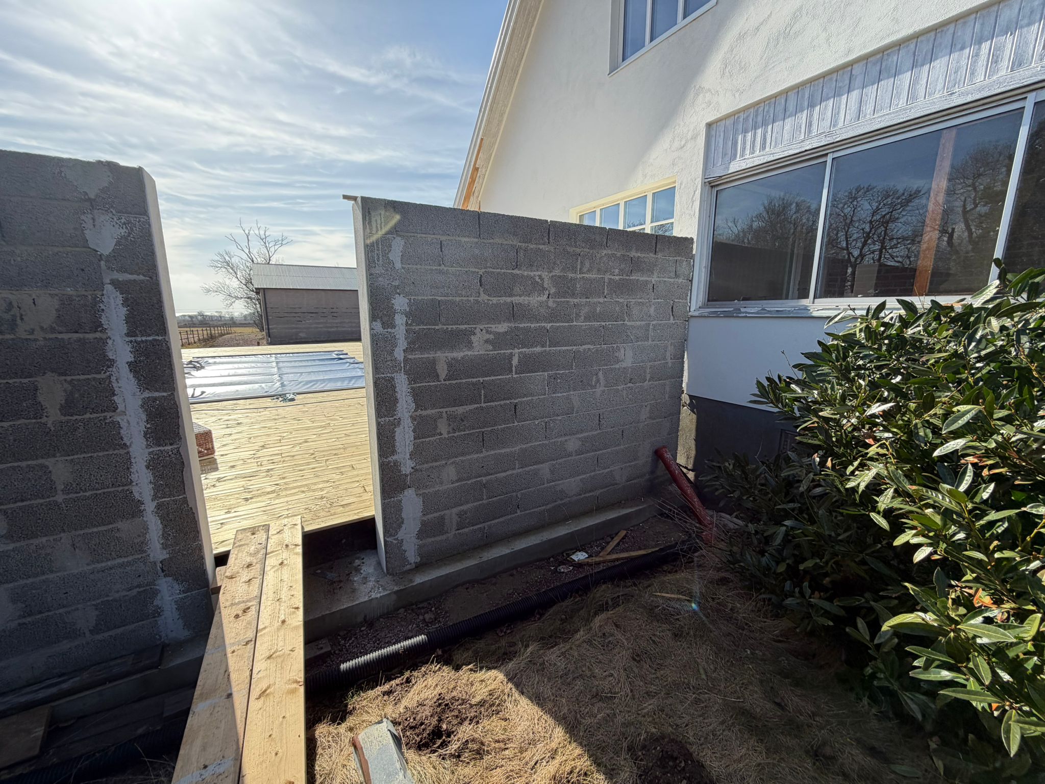 Trädäck med utemöbler vid putsad villa i Båstad efter helrenovering
