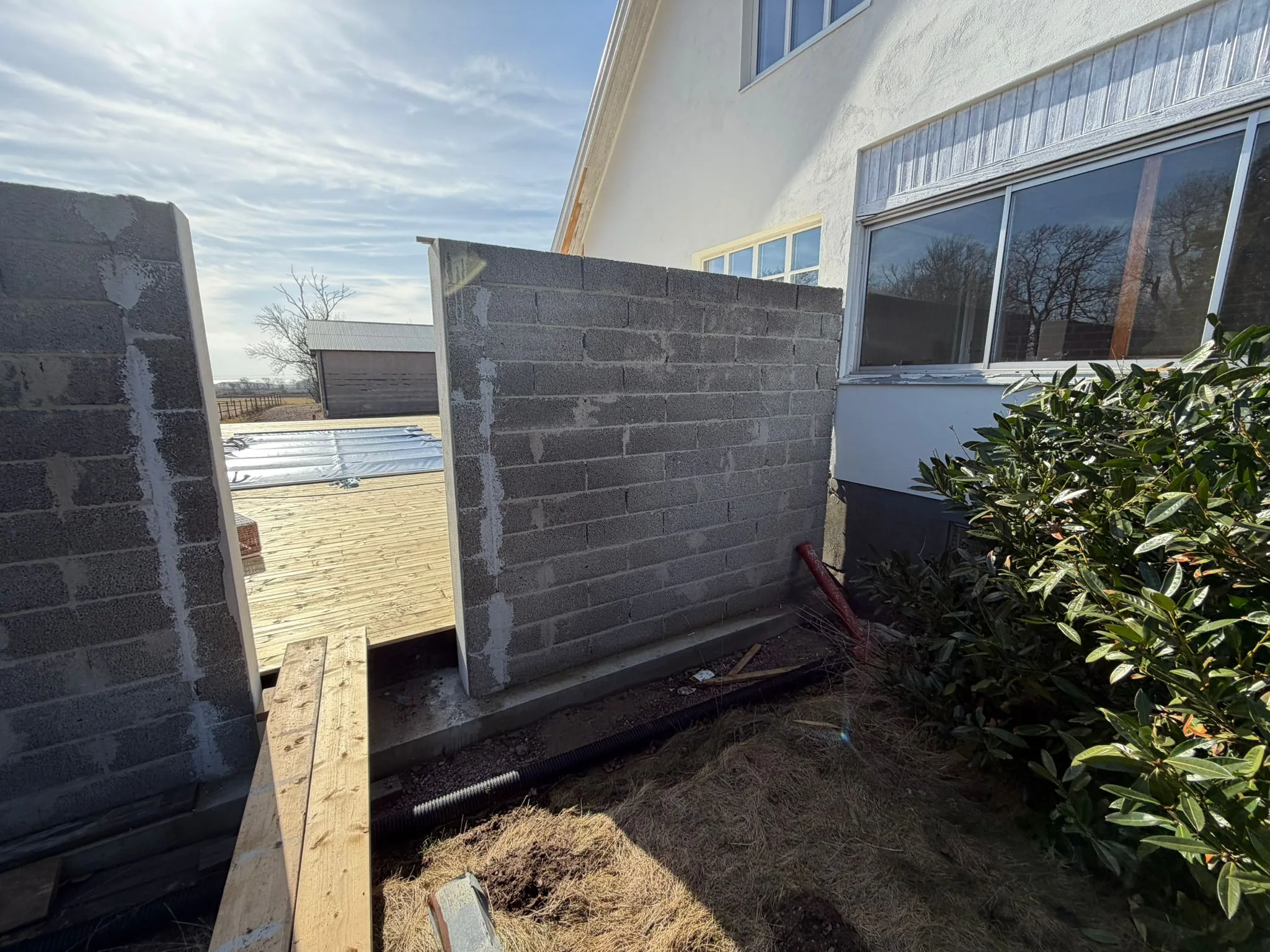 Trädäck med utemöbler vid putsad villa i Båstad efter helrenovering