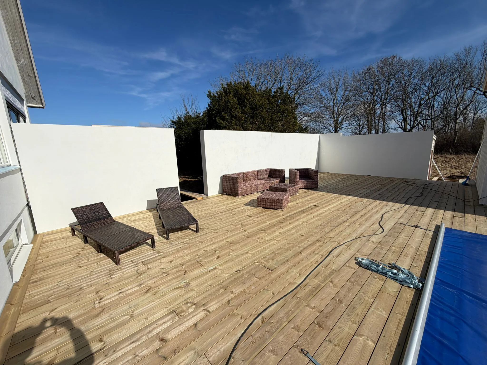 Sidovy av nybyggd cementblocksmur vid putsrenoverat hus i Båstad